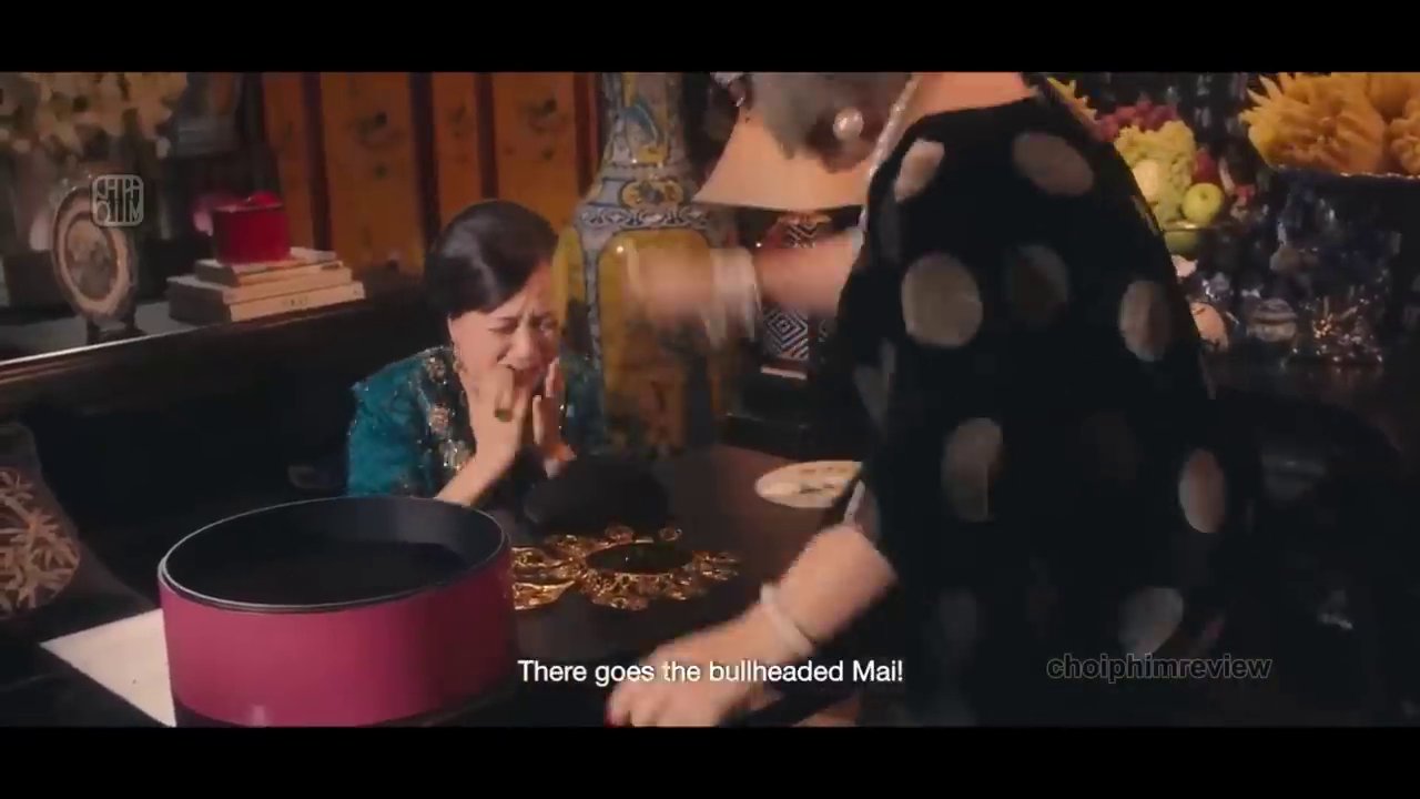 Cảnh bà Mai nhìn Quyên với ánh mắt lạnh lùng, đầy phán xét trong bữa tiệc, trong khi Quyên cố gắng giữ bình tĩnh.