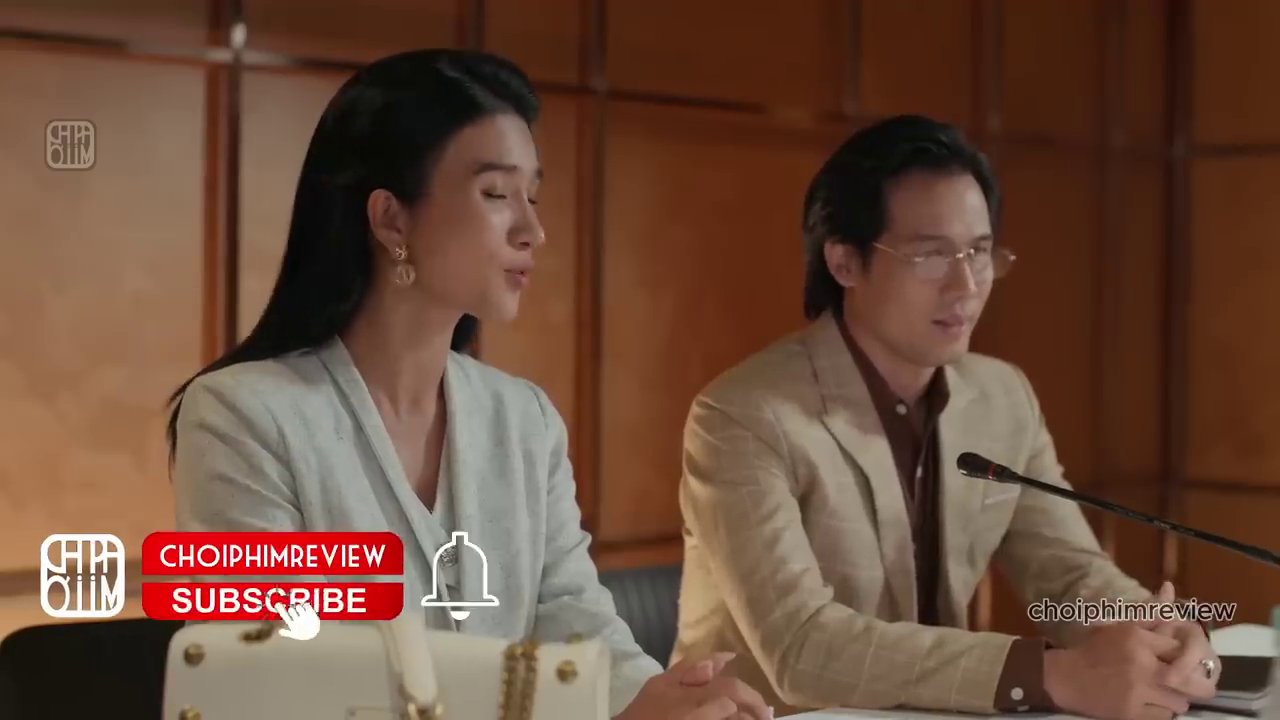 Cảnh Trang và Nam đứng trên bục họp báo, gương mặt căng thẳng nhưng cố tỏ ra bình tĩnh trước ống kính.